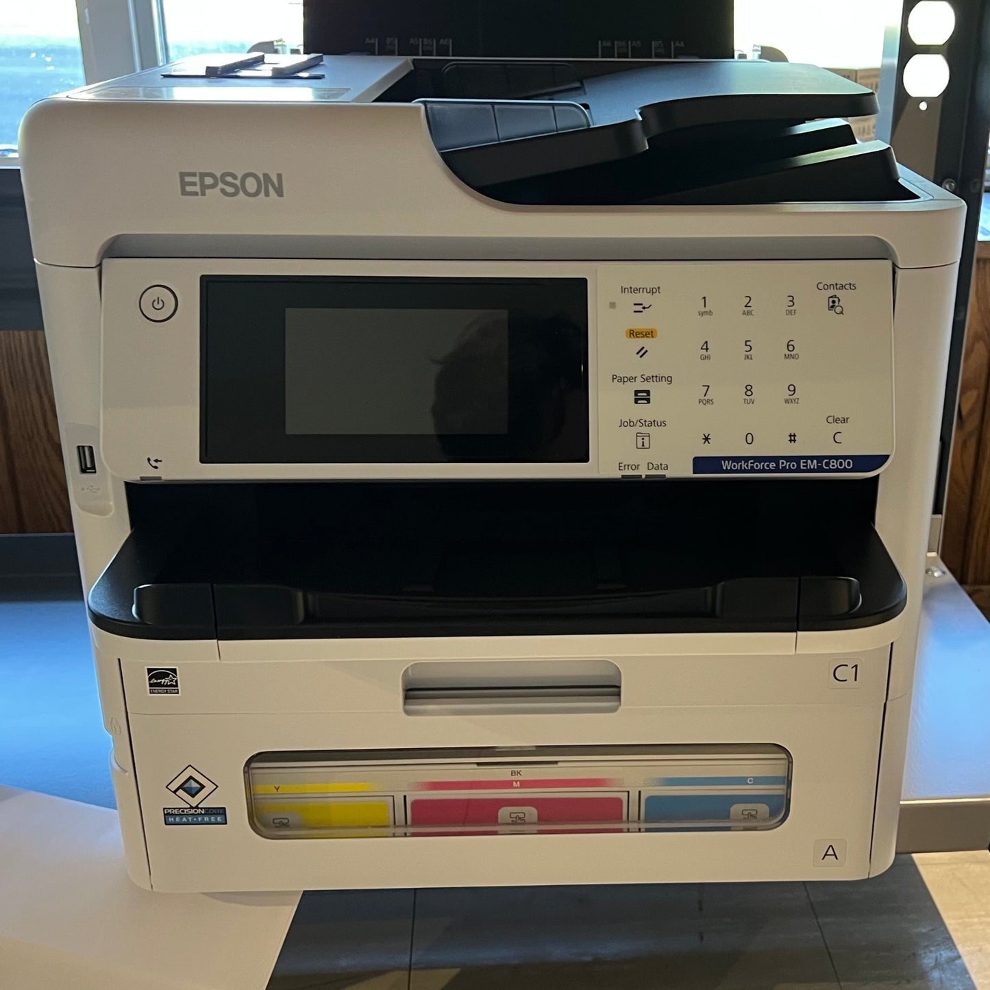 Epson printer on a table with a wooden floor and window in the background