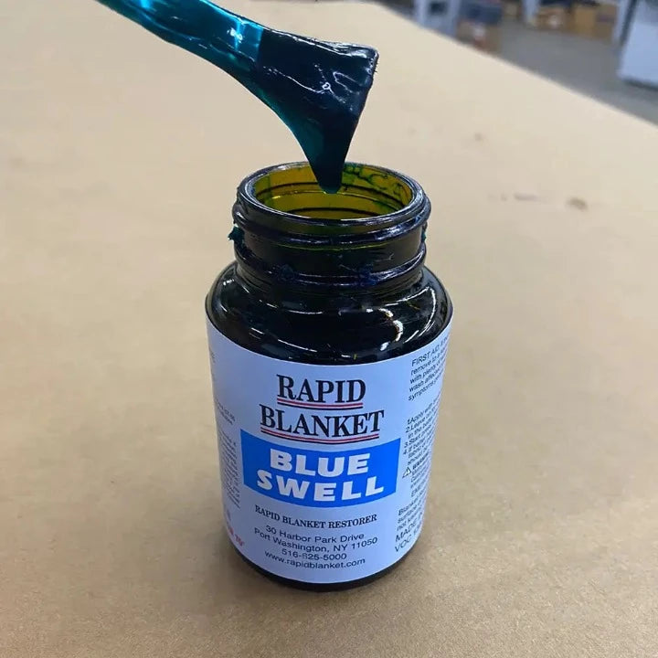 Rapid Blanket Blue Swell blanket restorer varnish being lifted with brush from open bottle for offset printing press maintenance